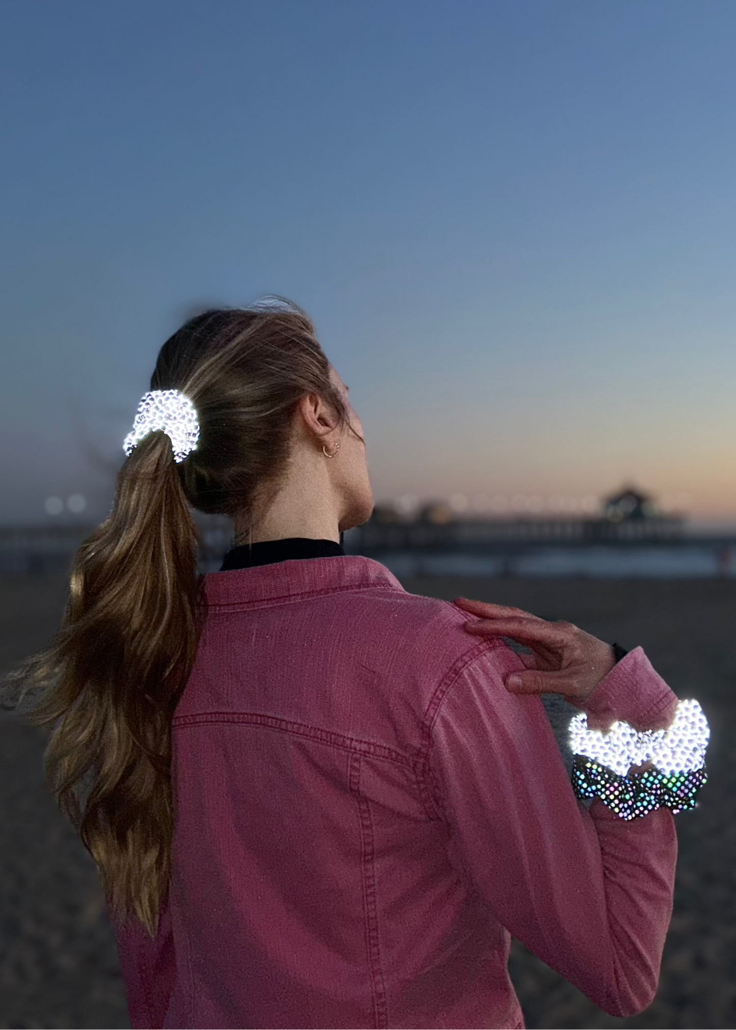 Reflective scrunchies in Honey Comb and rainbow pattern worn in hair and wrist on the beach